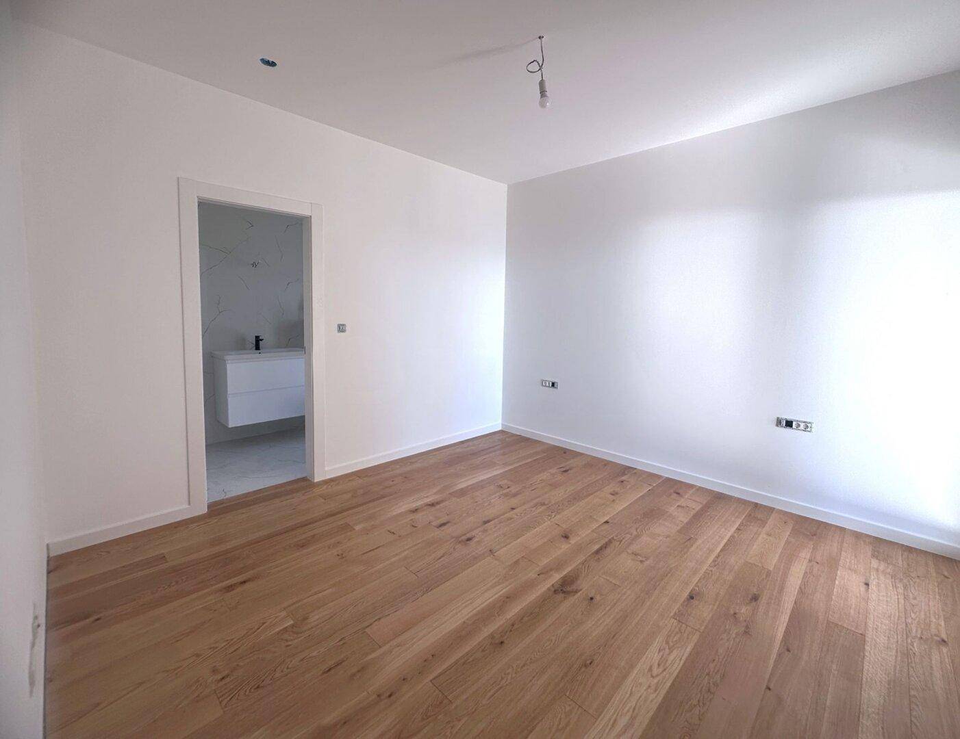 Helles Schlafzimmer mit Holzboden und direktem Zugang zum Badezimmer.