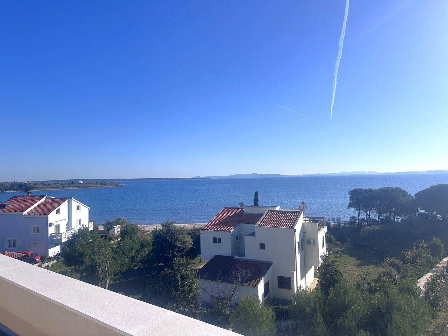 Sonnige Terrasse mit Panoramablick auf das glitzernde Meer.