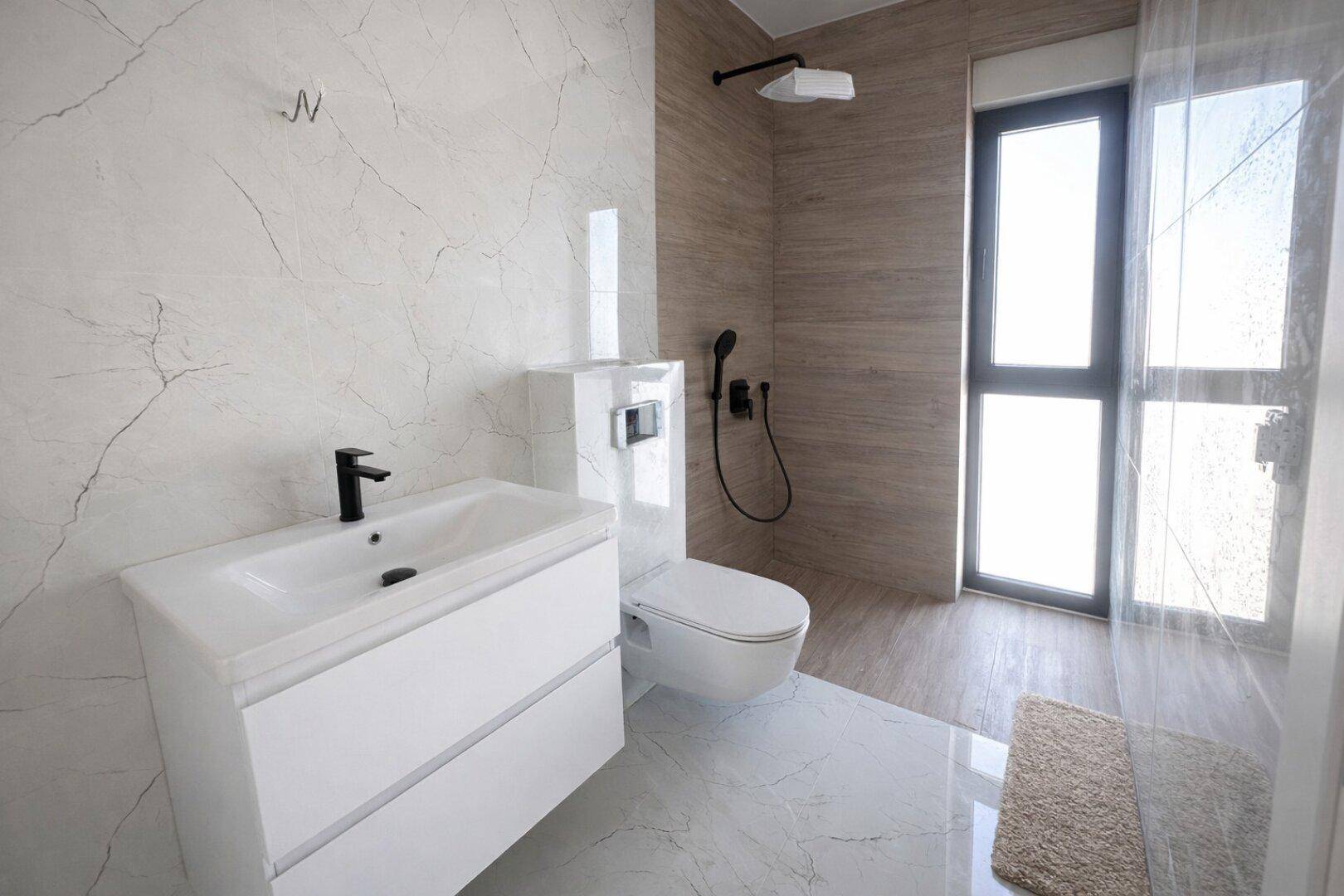 Modernes Badezimmer mit Waschtisch, wandhängendem WC und großer Dusche.
