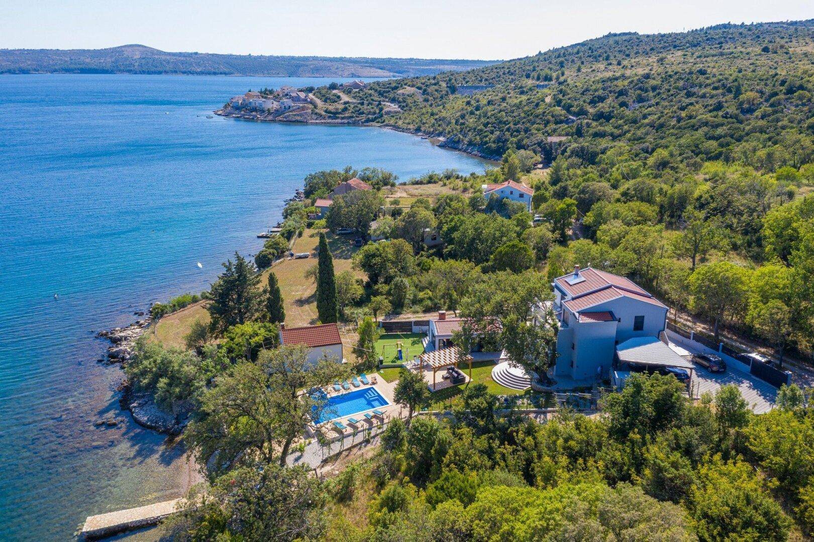 Luftaufnahme des Anwesens mit Pool, Gärten und direktem Zugang zum Meer in einer malerischen Bucht.