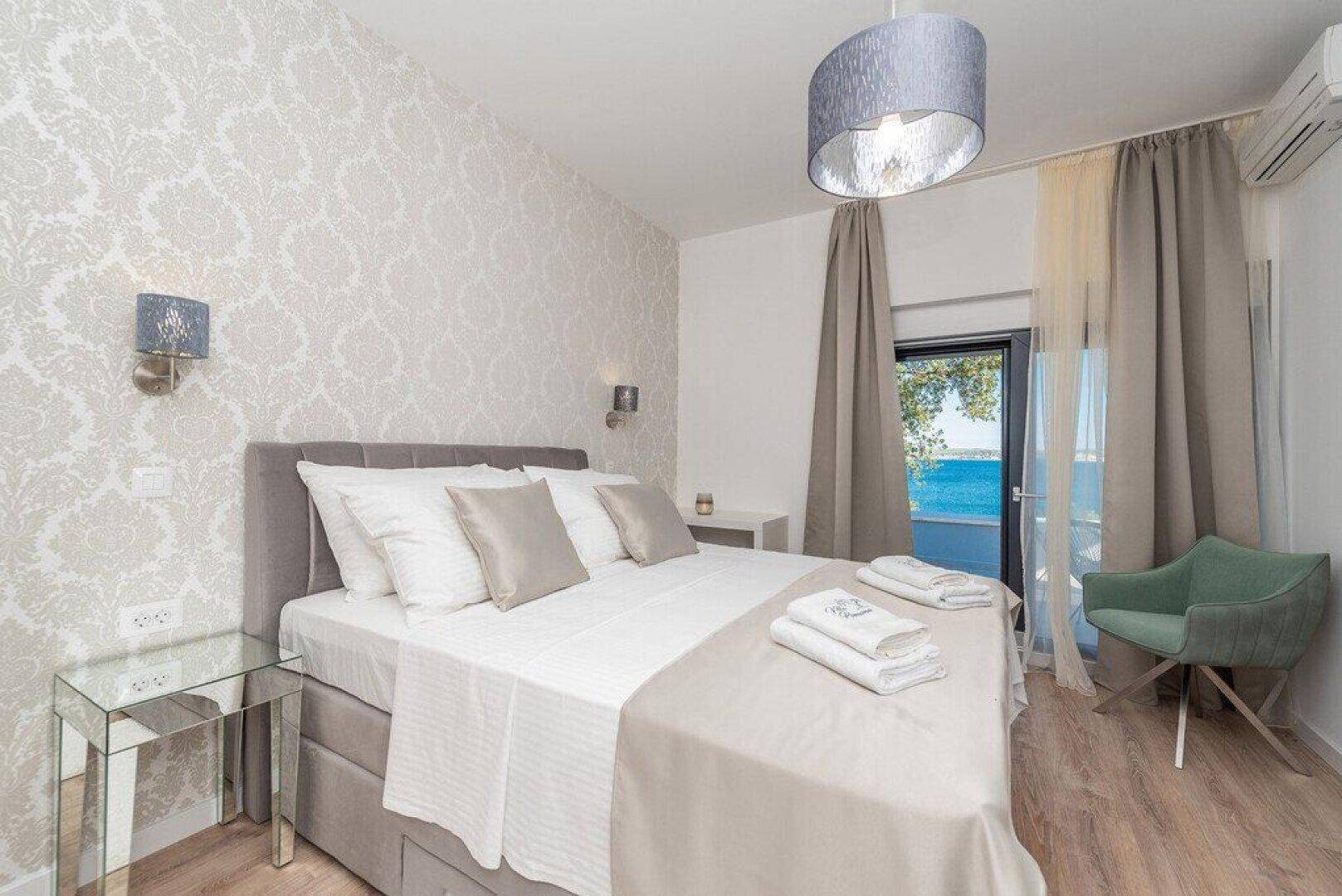 Helles Schlafzimmer mit Meerblick, Doppelbett und moderner Einrichtung, inklusive Klimaanlage.