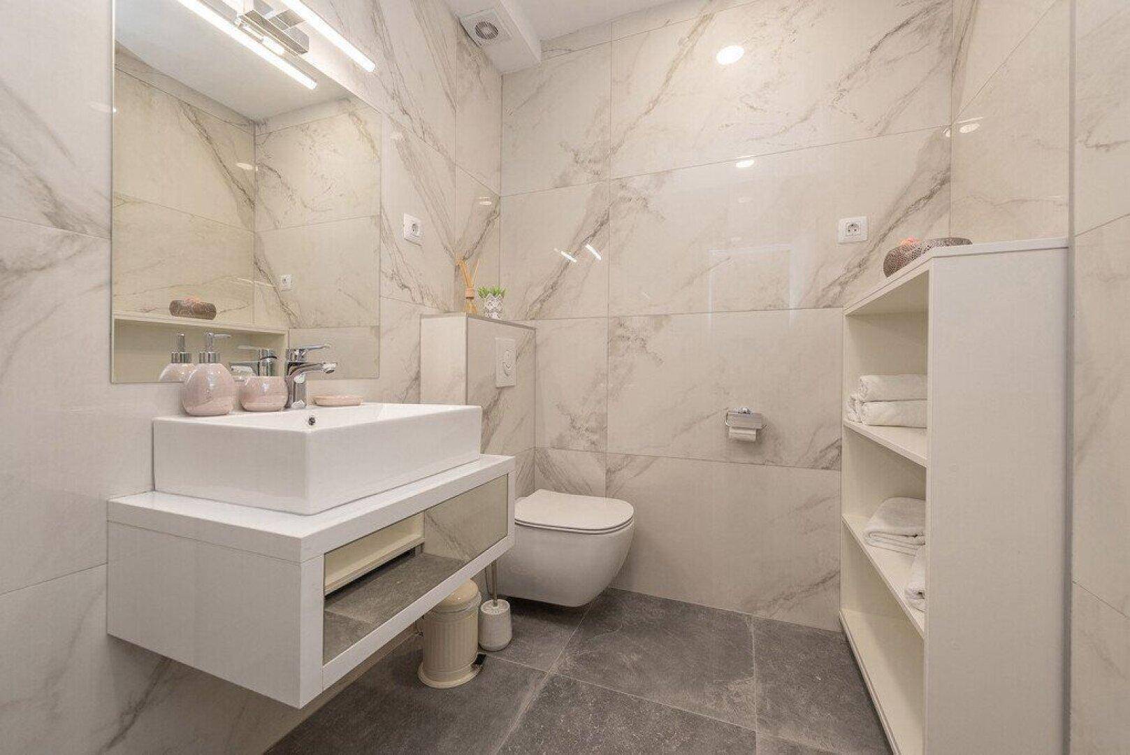 Stilvolles Badezimmer mit schwebendem Waschtisch, Wand-WC und großformatigen Marmorfliesen.