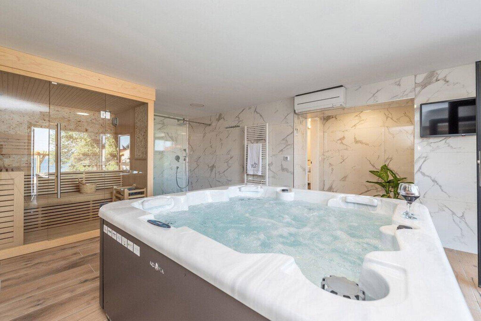 Luxuriöser Wellnessbereich mit Whirlpool, Sauna und Meerblick, ideal zur Entspannung.
