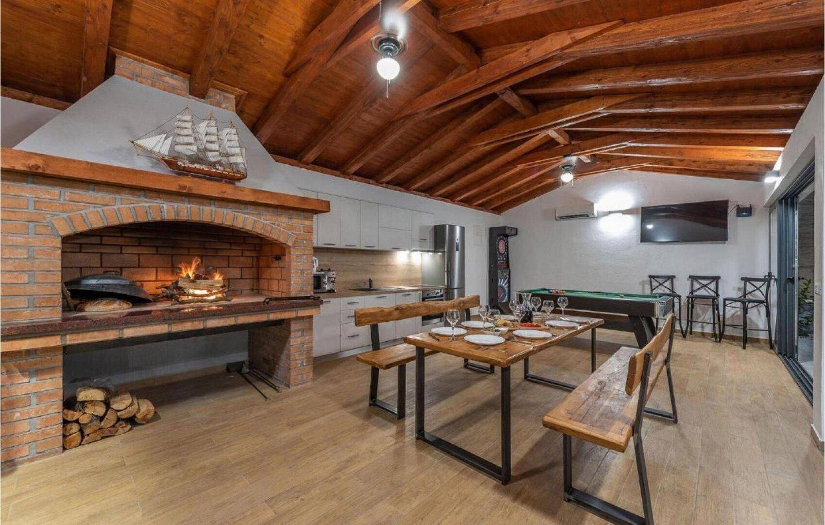 Rustikaler Wohn- und Essbereich mit Holzbalkendecke, Kamin und integrierter Küche.