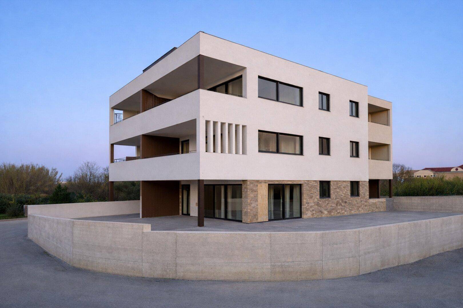 Neubau mit moderner Architektur, weißer Fassade und Natursteinverkleidung im Erdgeschoss.