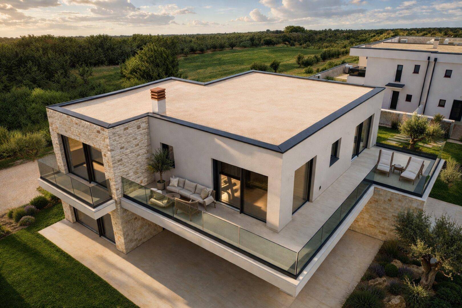 Luftaufnahme einer modernen Villa mit Flachdach, Balkon und Terrasse in grüner Landschaft.