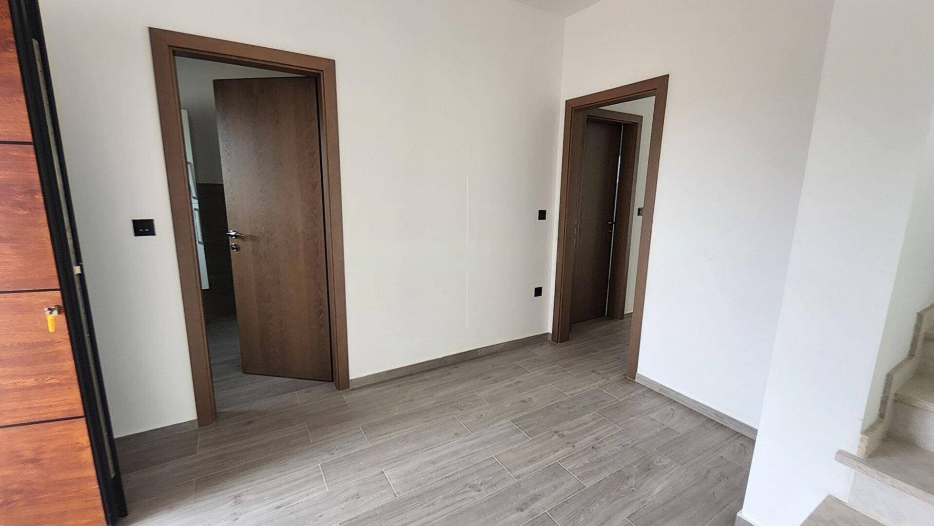 Heller Flurbereich mit Holztüren und modernem Bodenbelag in einem Neubau.