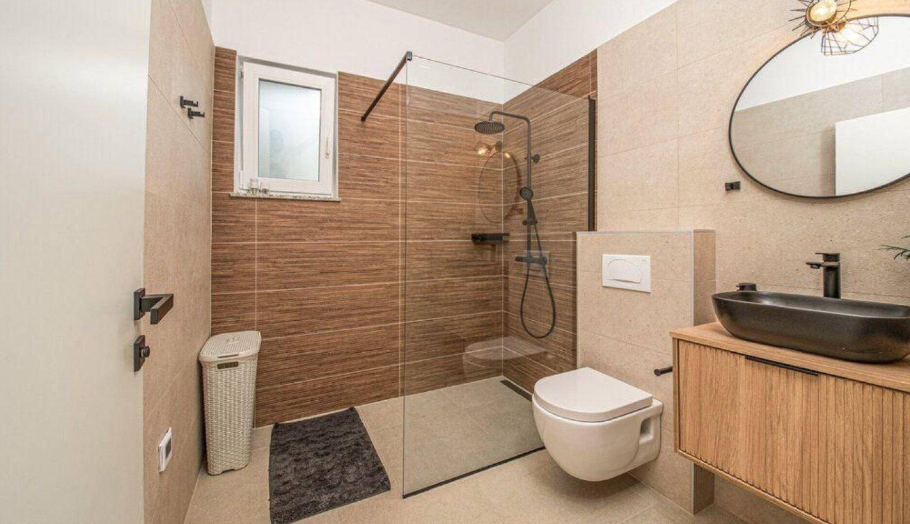 Modernes Badezimmer mit begehbarer Dusche, Hänge-WC und stilvollem Waschbecken.