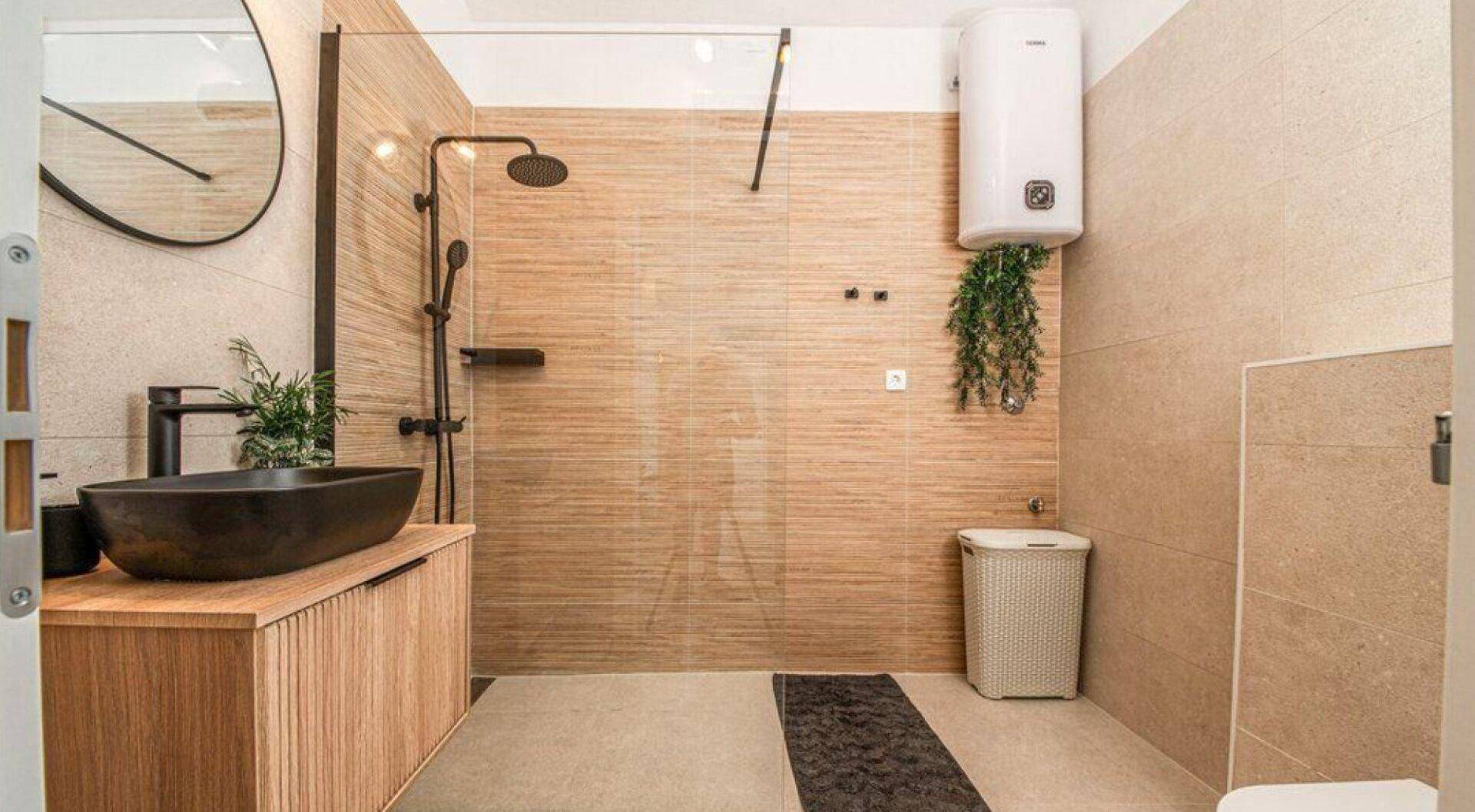 Modernes Badezimmer mit begehbarer Dusche, Aufsatzwaschbecken und beigen Fliesen.