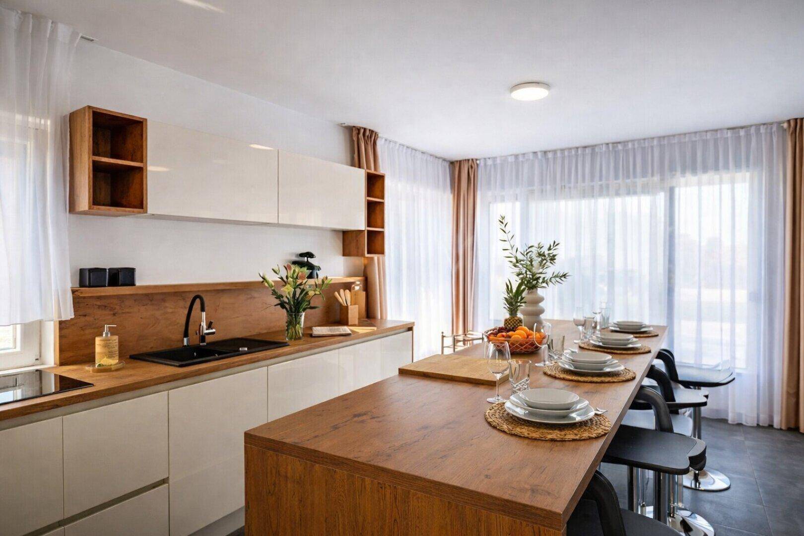 Moderne Küche mit Holztheke, weißen Schränken und integriertem Essbereich mit Barhockern.