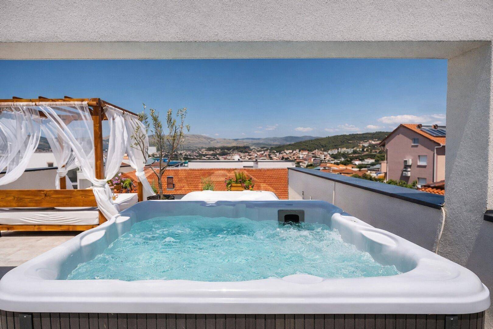 Sonniger Dachterrassenbereich mit Whirlpool und weitem Blick über die Stadt und die Landschaft.