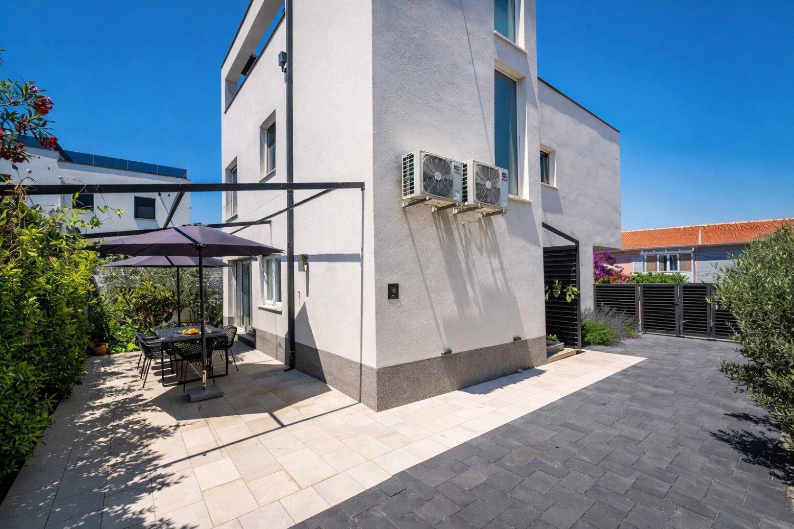 Moderne Gebäudefassade mit Klimaanlagen und einer schattigen Terrasse für Mahlzeiten im Freien.