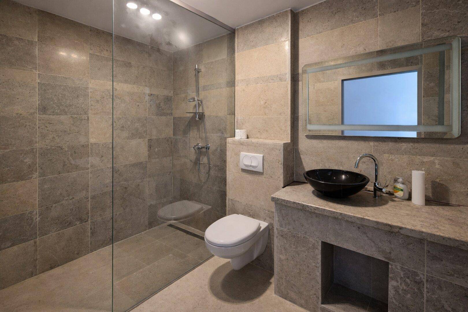Modernes Badezimmer mit begehbarer Dusche, Wand-WC und beleuchtetem Spiegel.