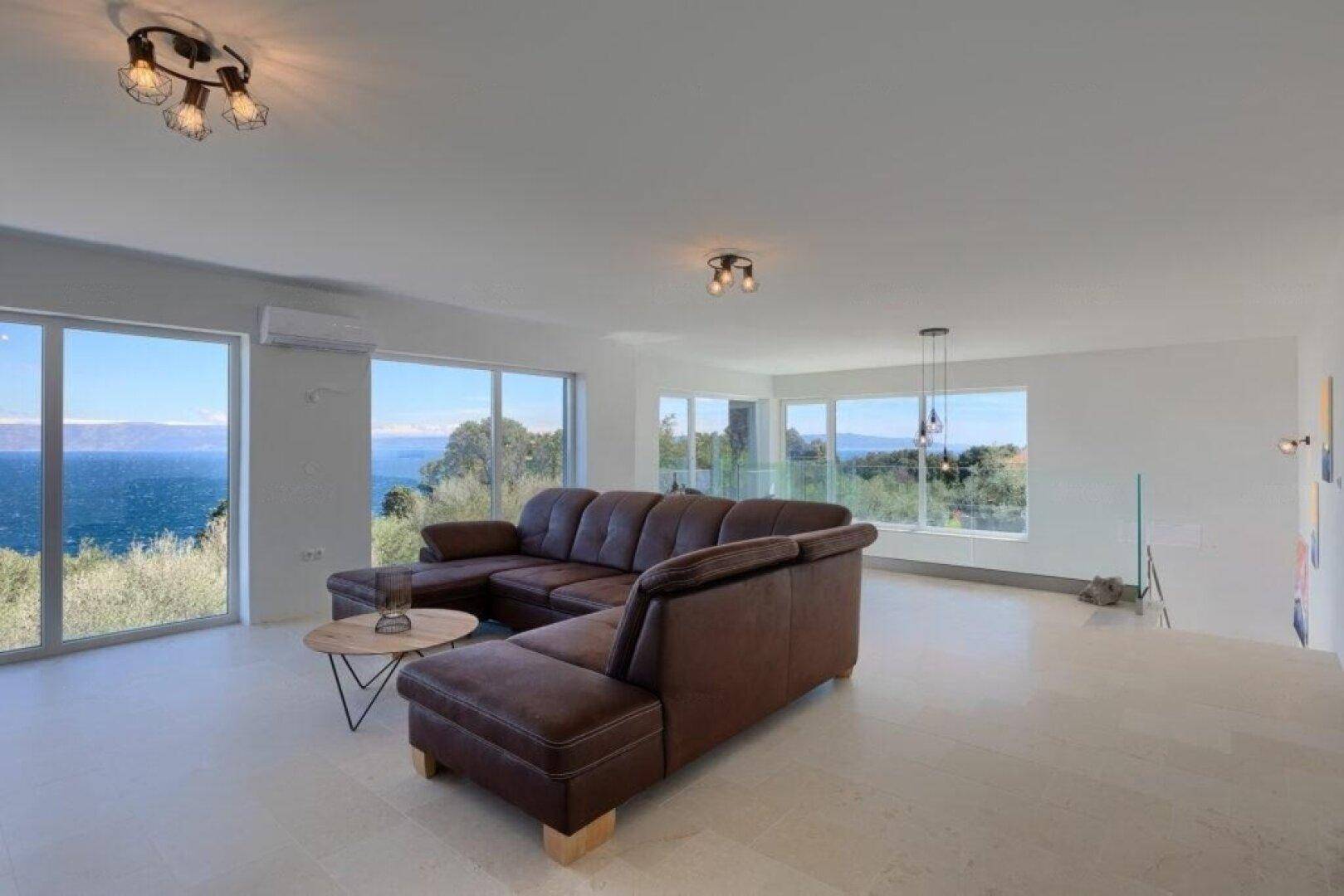 Geräumiges Wohnzimmer mit moderner Einrichtung, hohen Decken und weitem Meerblick.