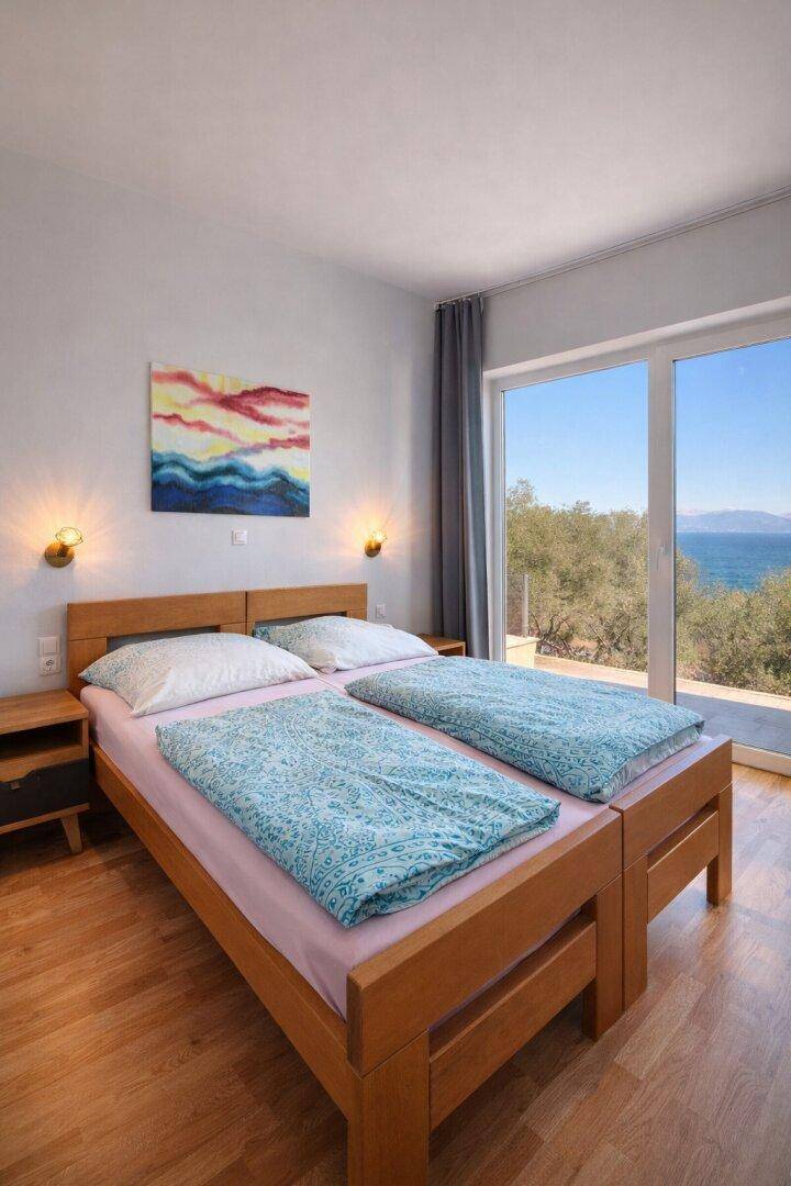 Gemütliches Schlafzimmer mit Holzbett, Parkettboden und Meerblick.