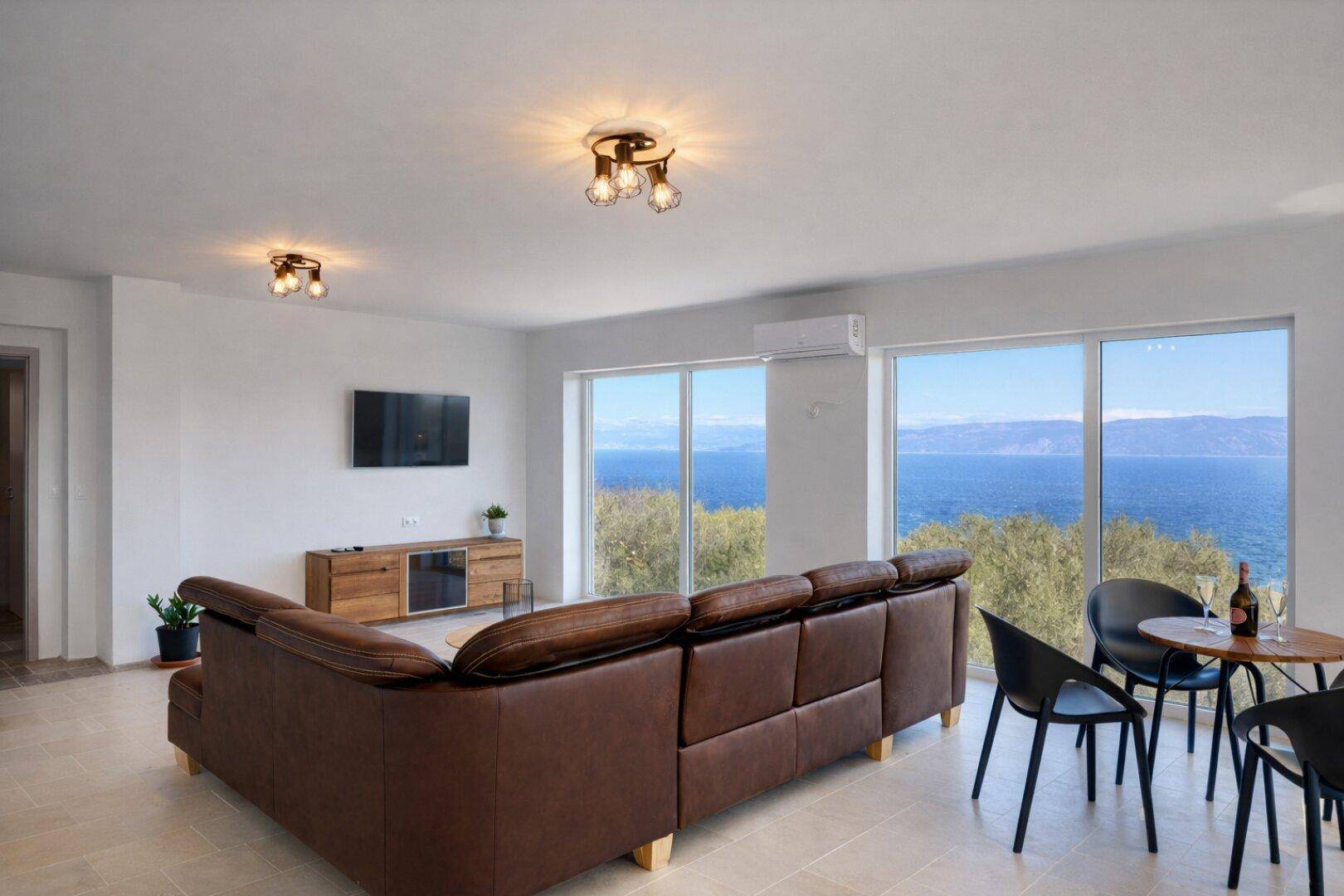 Offener Wohnbereich mit Sofa, Esstisch und beeindruckendem Meerblick.
