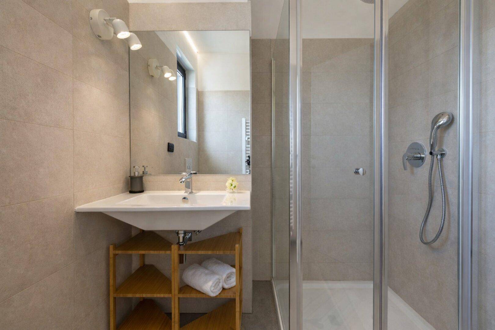 Modernes Badezimmer mit begehbarer Dusche, Einzelwaschbecken und hellen Fliesen.