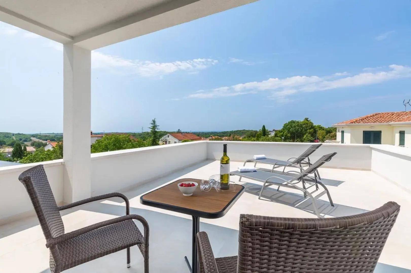 Geräumige Dachterrasse mit Gartenmöbeln, Sonnenliegen und einem weiten Blick in die Umgebung.