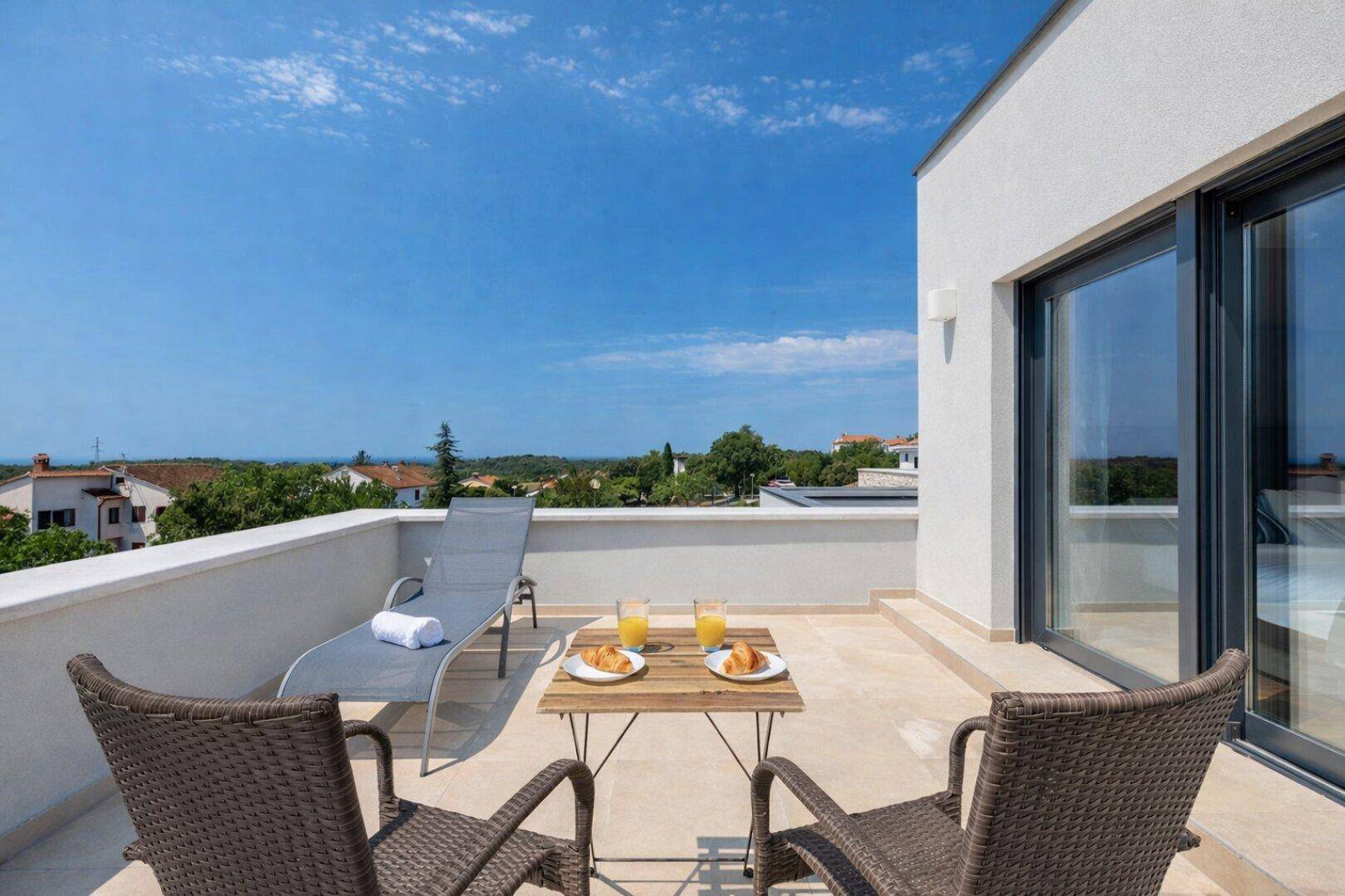 Sonnige Dachterrasse mit Sitzgelegenheiten, Liegestuhl und weitem Blick über die Umgebung.