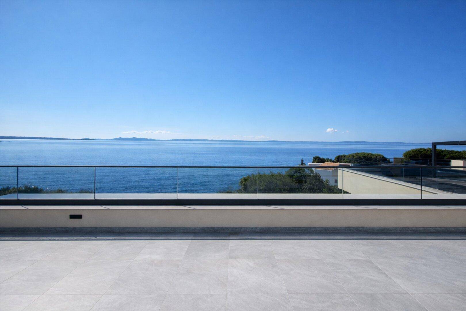 Weitläufige Dachterrasse mit atemberaubendem Meerblick und moderner Glasbrüstung.