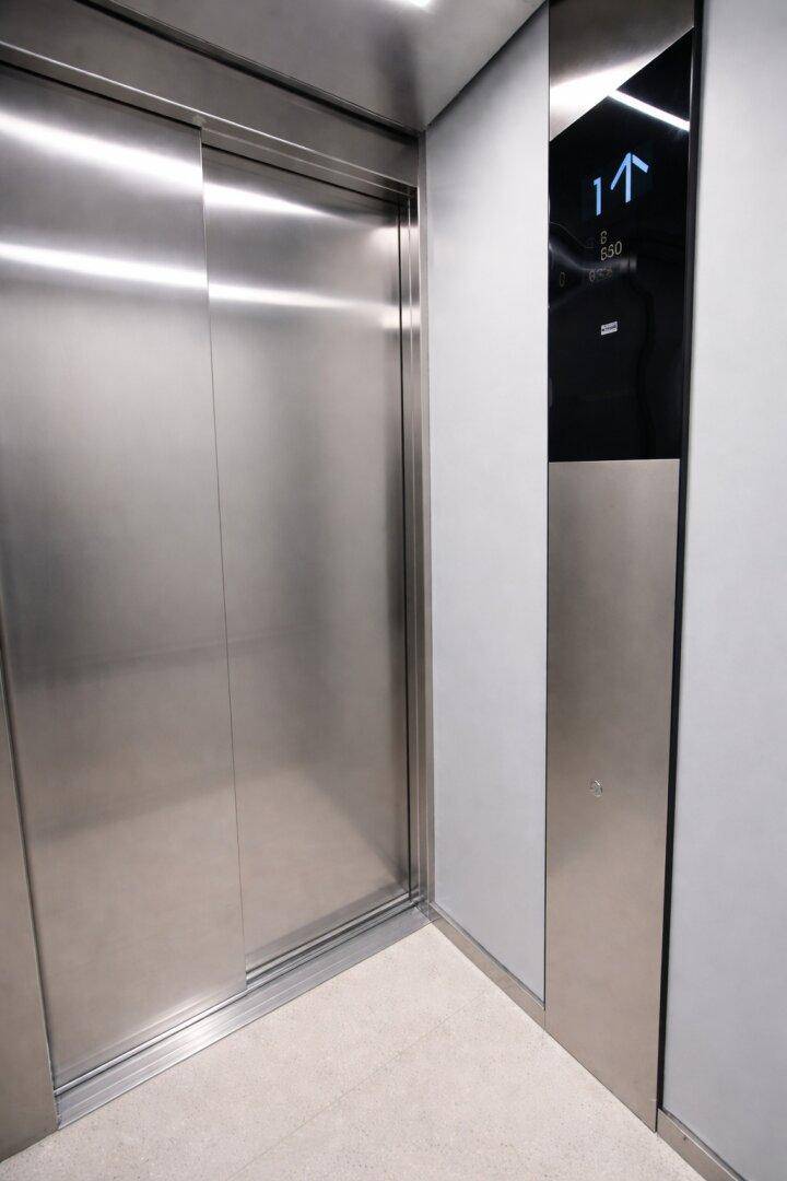Moderner Aufzug mit Edelstahloberflächen und digitaler Etagenanzeige im Gebäude.