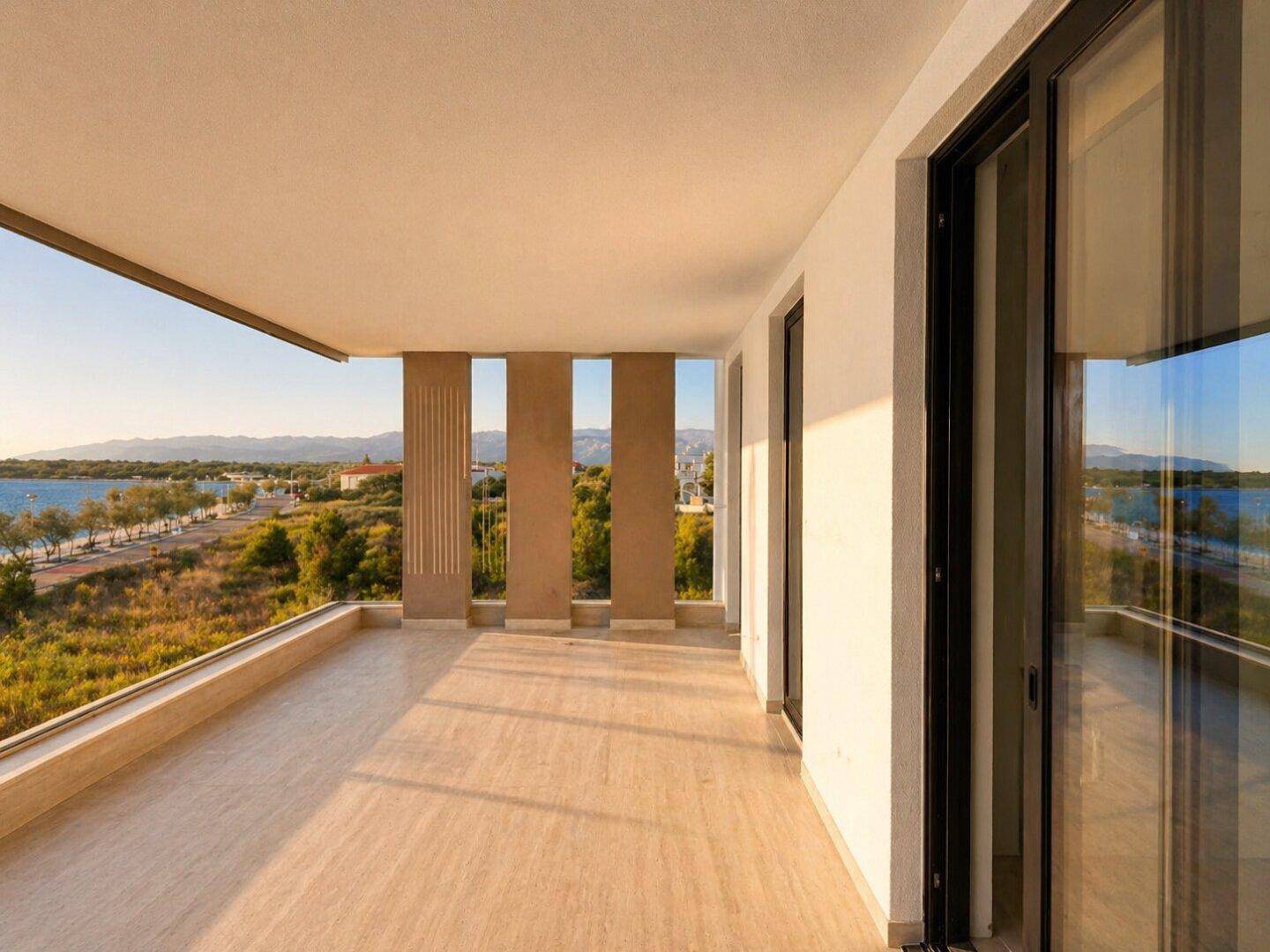 Geräumiger Balkon mit Fliesenboden und weitem Blick auf das Meer und die Küstenlandschaft.