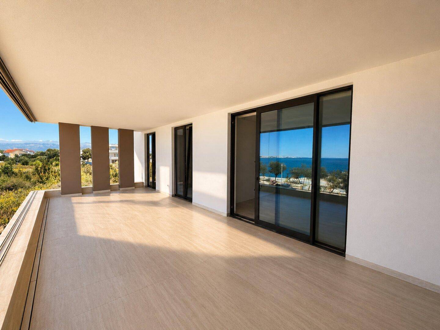 Großer, sonniger Balkon mit Fliesenboden und weitem Blick auf die Umgebung und das Meer.