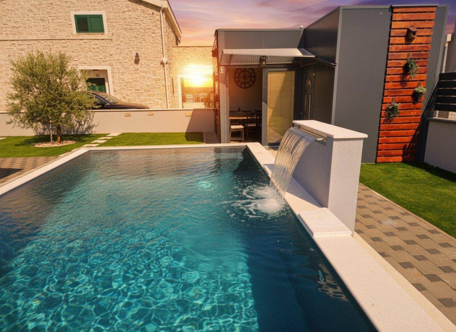 Detailansicht des Pools mit elegantem Wasserfall und gepflastertem Bereich bei Sonnenuntergang.