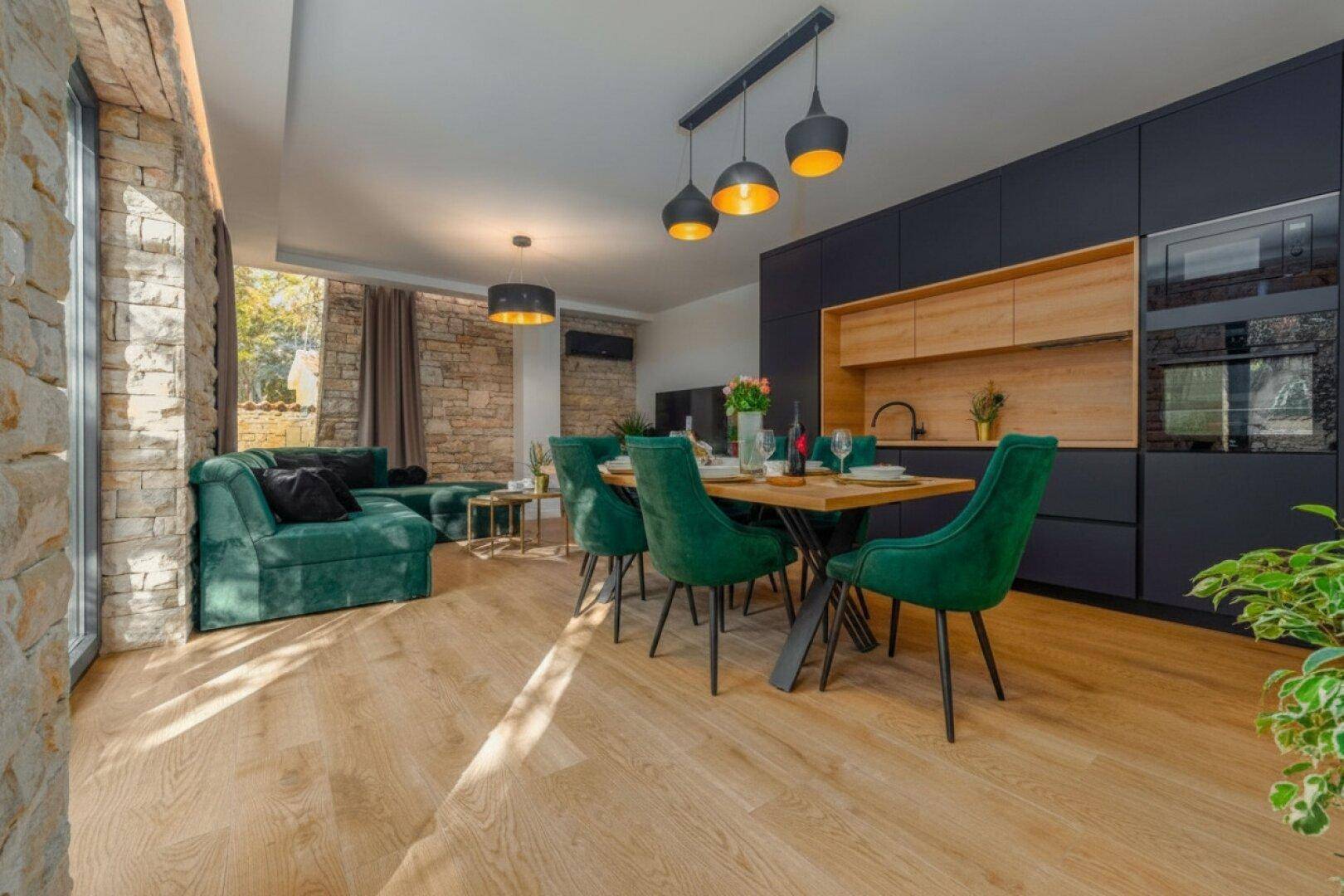 Heller Wohn- und Essbereich mit integrierter Küche, Holzboden und Zugang zur Terrasse.
