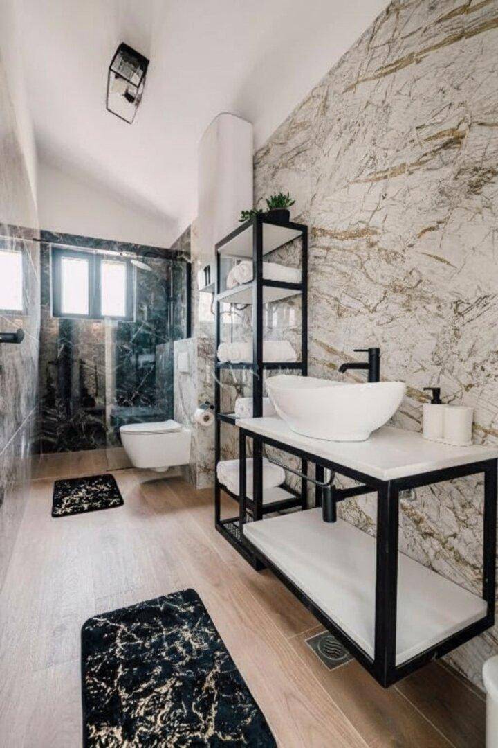 Elegantes Badezimmer mit Marmoroptik-Fliesen, modernem Waschtisch und offener Duschzone.