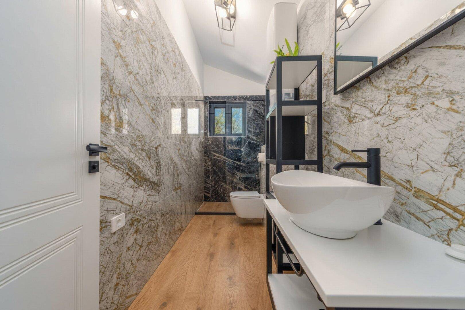 Helles Badezimmer mit Fenster, Marmorfliesen und modernem Design, gut beleuchtet.