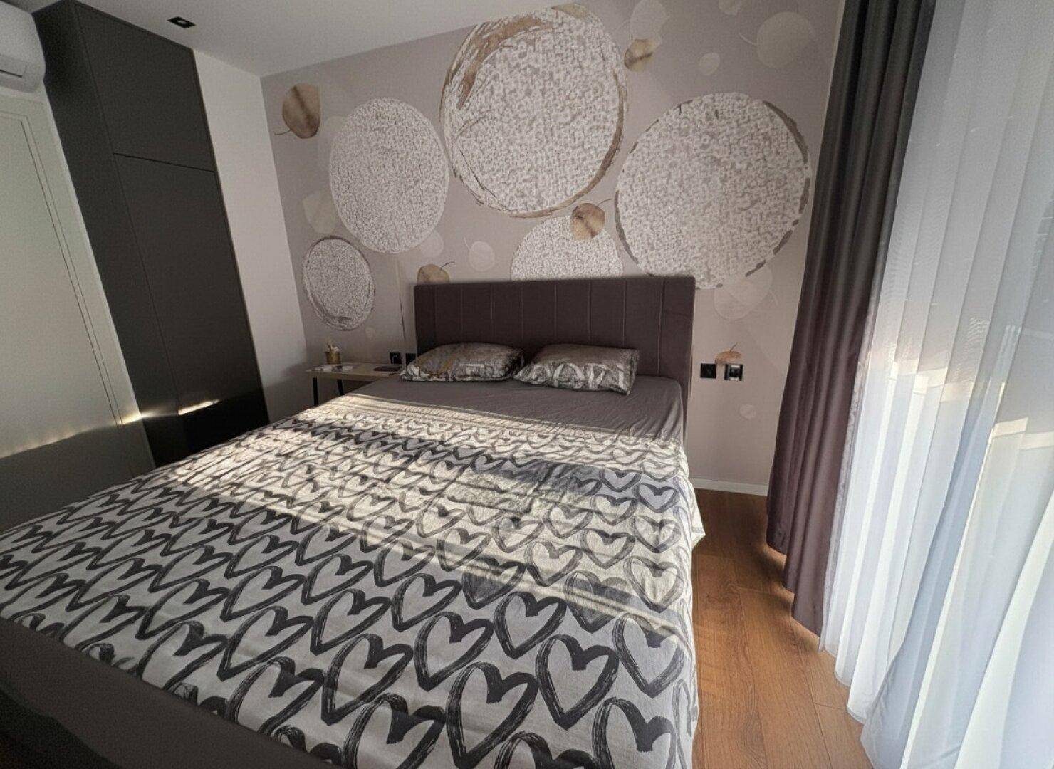 Schlafzimmer mit Doppelbett, Holzboden und kreativer Wanddekoration.