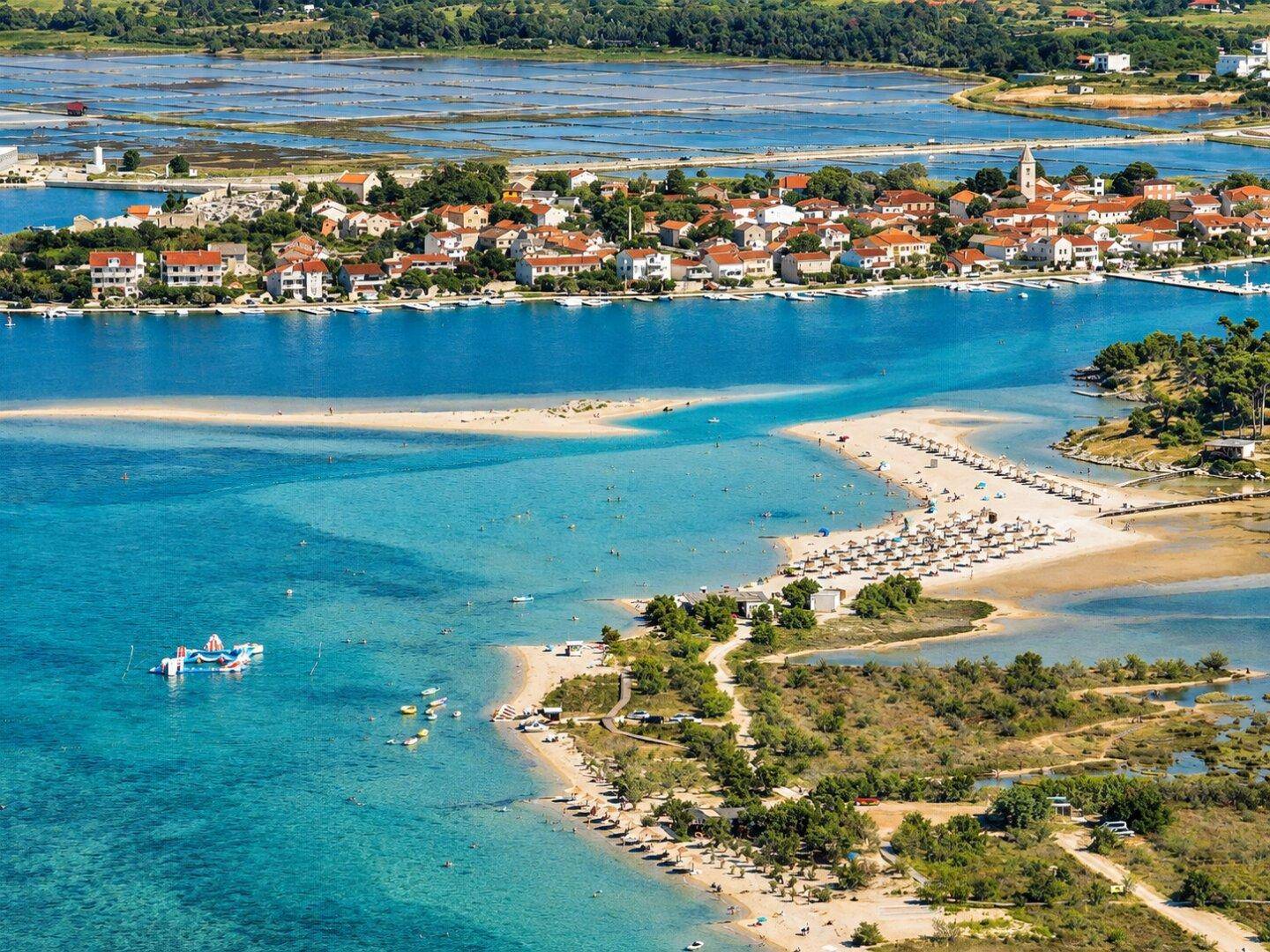 Malerische Luftansicht einer Küstenregion mit Sandstränden, klarem Wasser und einer charmanten Stadt.