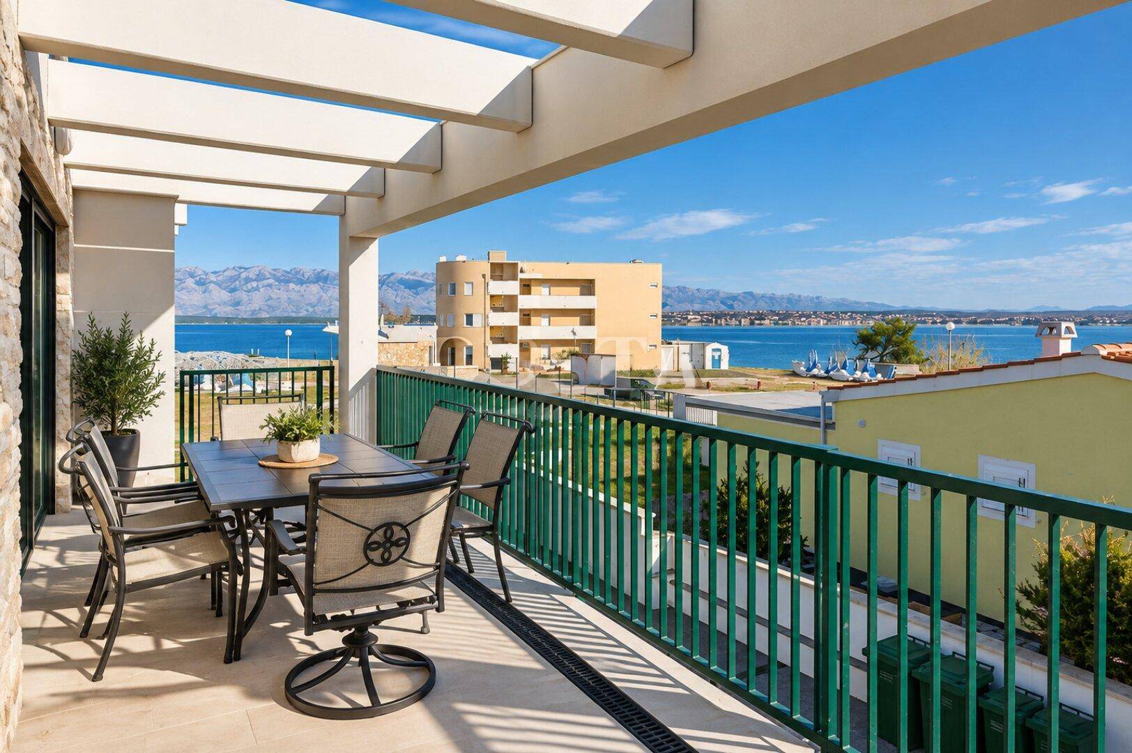 Geräumiger Balkon mit Esstisch, Stühlen und weitem Blick auf das Meer und die Berge.