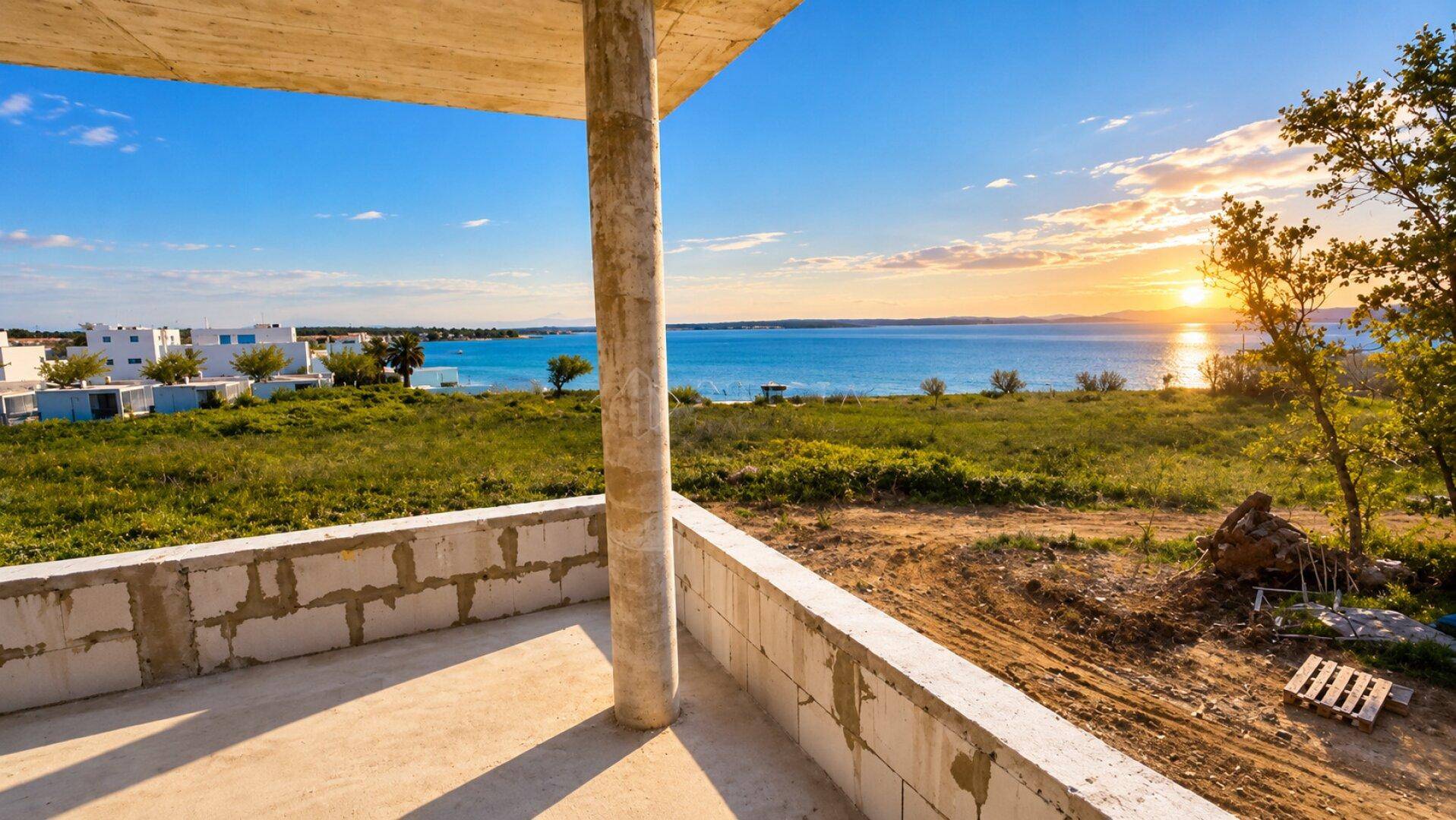 Unfertiger Balkon mit weitem Blick auf das Meer und die Küstenlandschaft bei Sonnenuntergang.