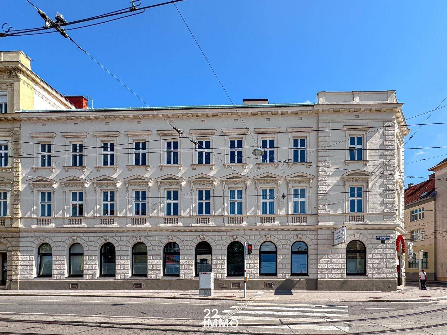 Historisches Gebäude mit klassischer Fassade und vielen Fenstern an einer belebten Straße.