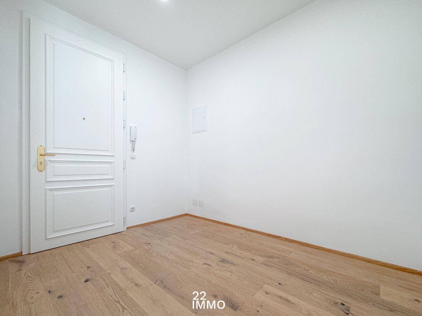 Heller Eingangsbereich mit Holzboden und weißer Tür, bereit zur individuellen Gestaltung.