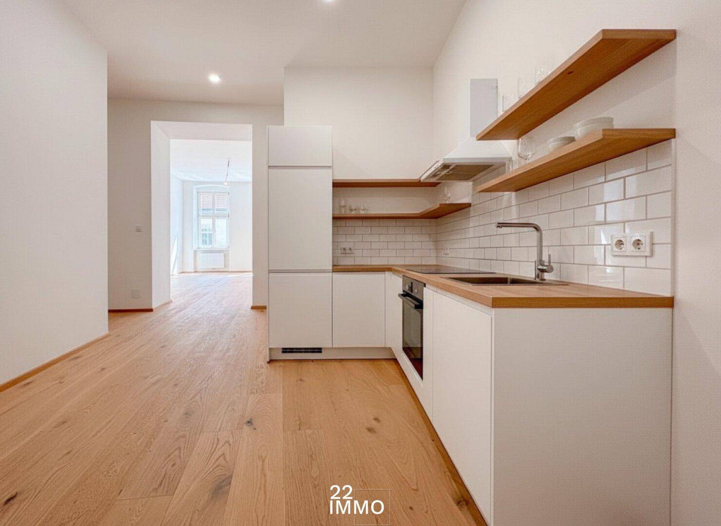 Moderne Einbauküche mit weißen Schränken, Holzregalen und Fliesenrückwand, hell und funktional.