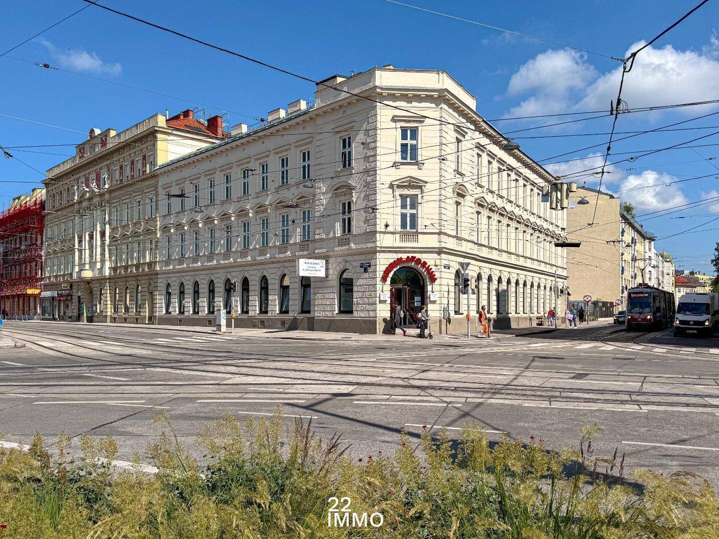 Historisches Eckgebäude mit klassischer Architektur an einer belebten Kreuzung in der Stadt.