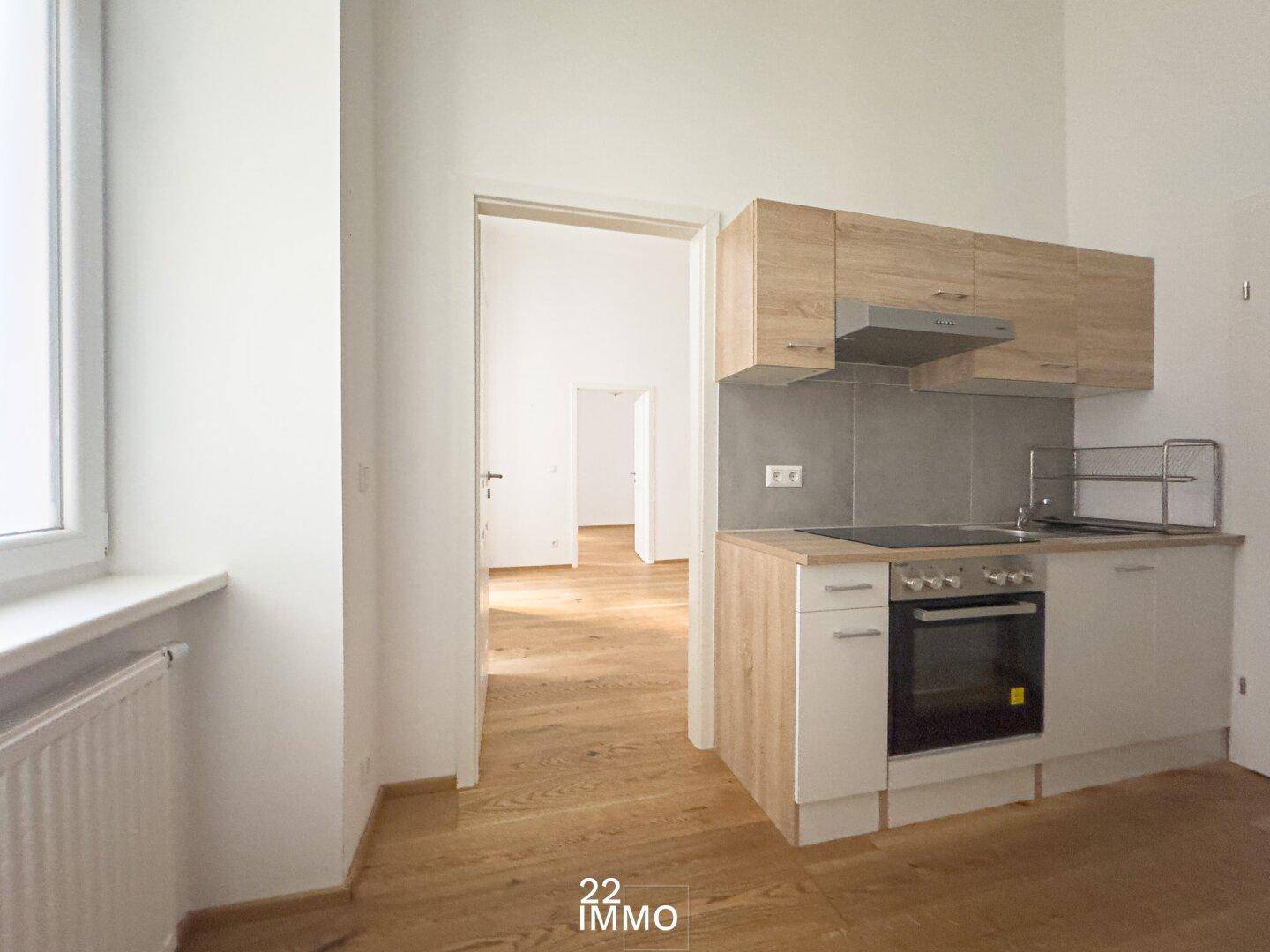 Kompakte Küchenzeile mit Holzfronten und integriertem Herd, ideal für kleine Wohnungen.