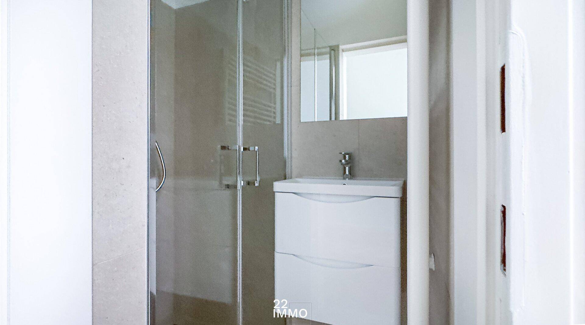 Modernes Badezimmer mit Duschkabine, Waschbeckenunterschrank und beheiztem Handtuchhalter.