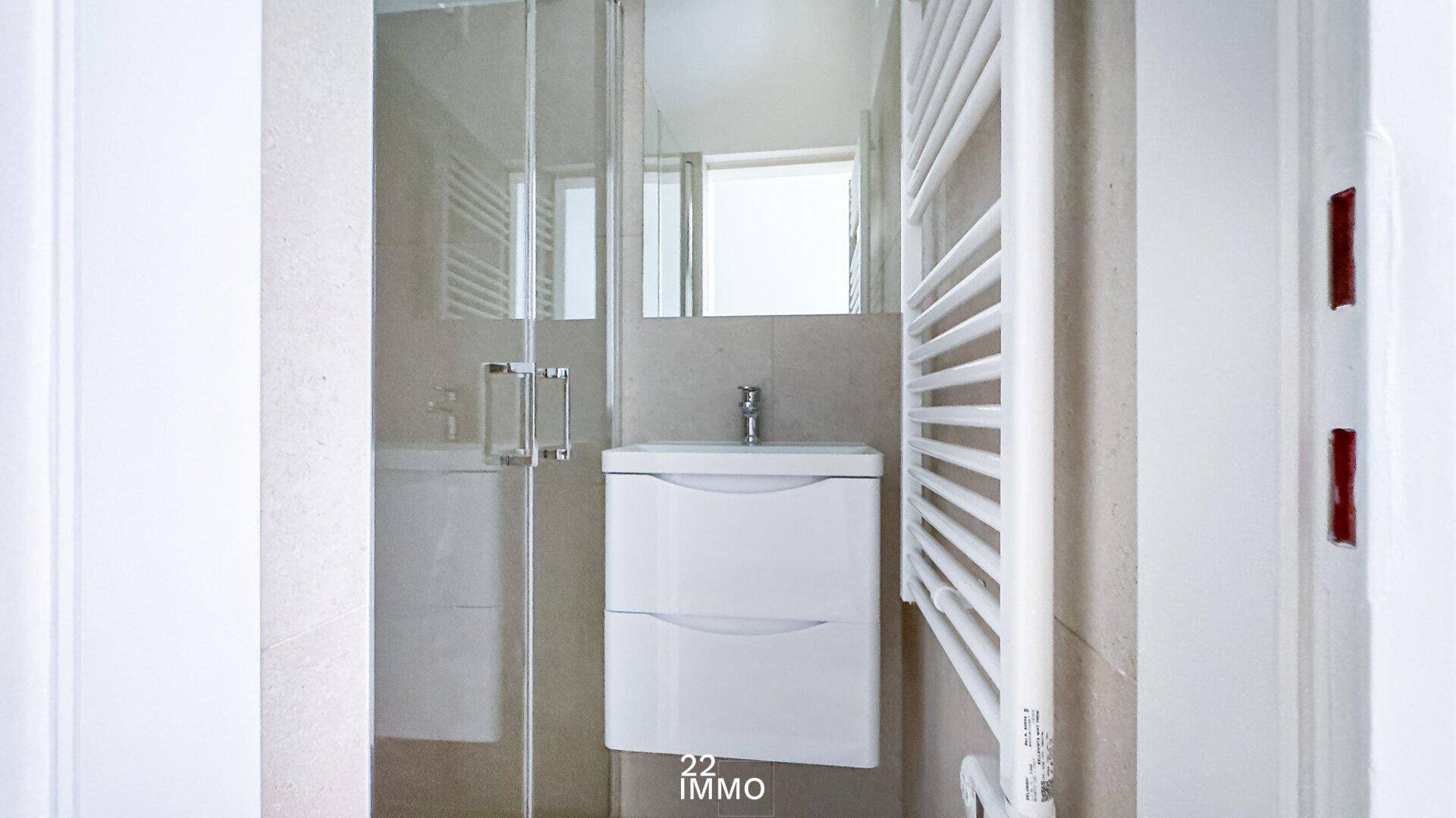 Modernes Badezimmer mit Duschkabine, Waschbeckenunterschrank und beheiztem Handtuchhalter.