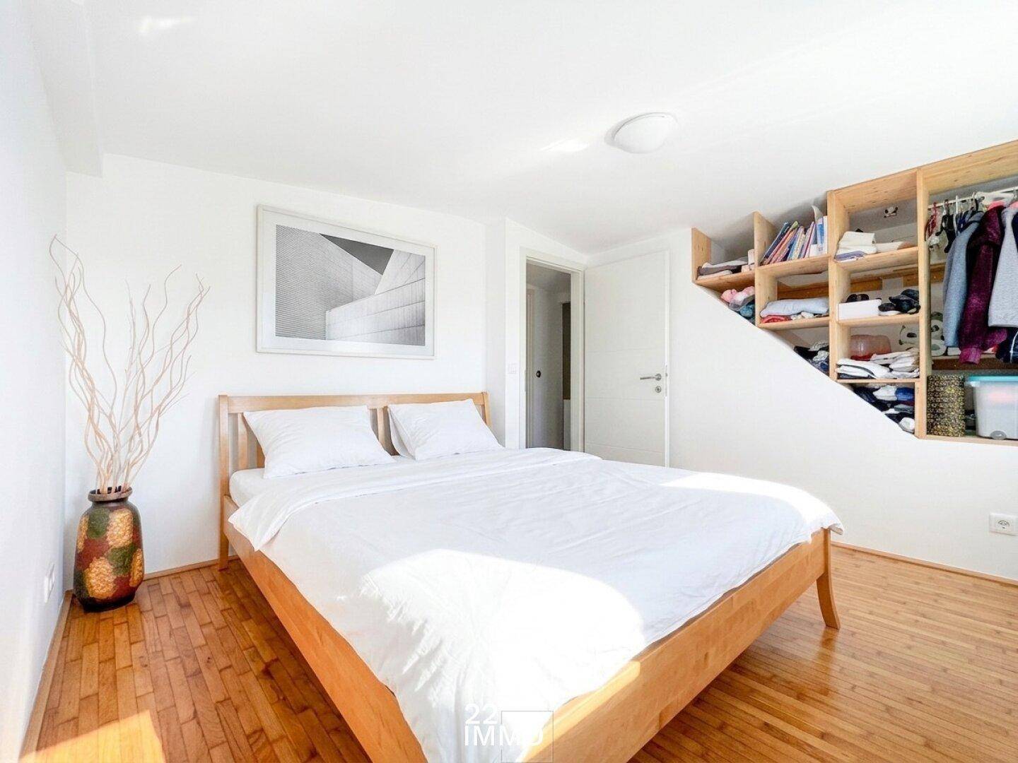 Gemütliches Schlafzimmer mit Holzbett, Holzboden und integriertem Stauraum unter der Dachschräge.