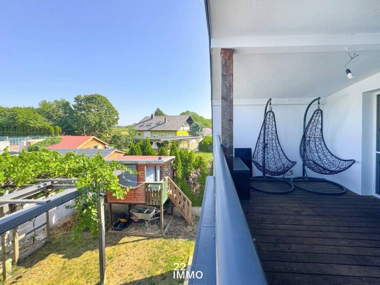 Geräumiger Balkon mit Holzboden und Hängesesseln, bietet einen weiten Blick ins Grüne.