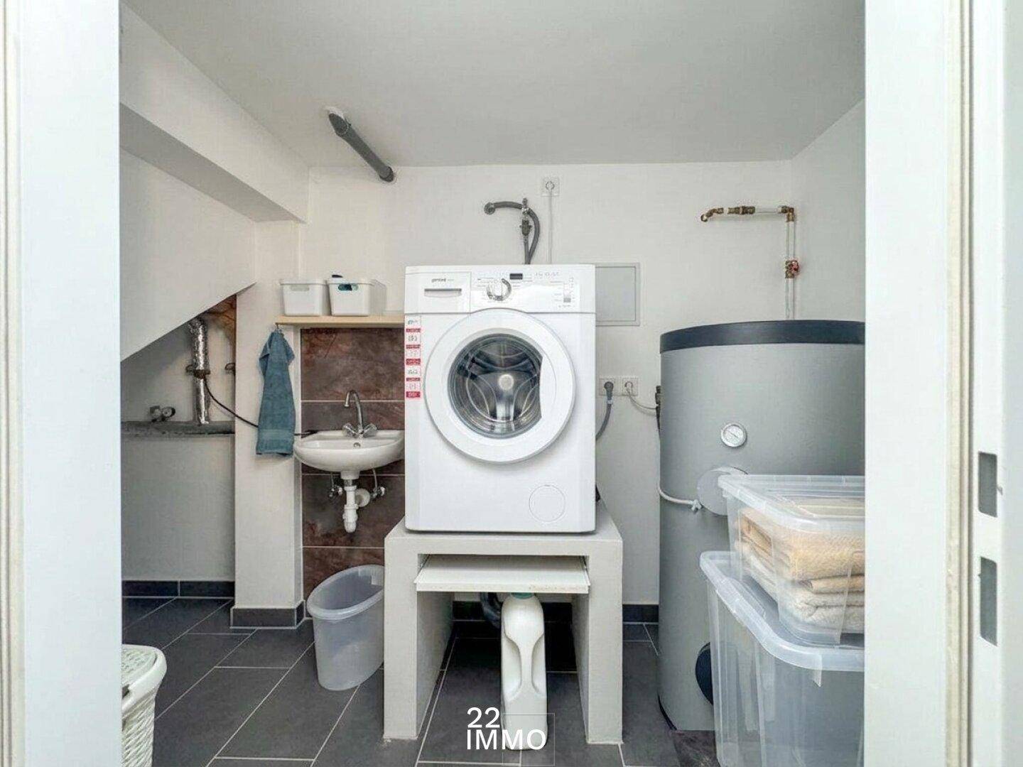 Praktischer Hauswirtschaftsraum mit Waschmaschine, Spülbecken und Warmwasserspeicher.