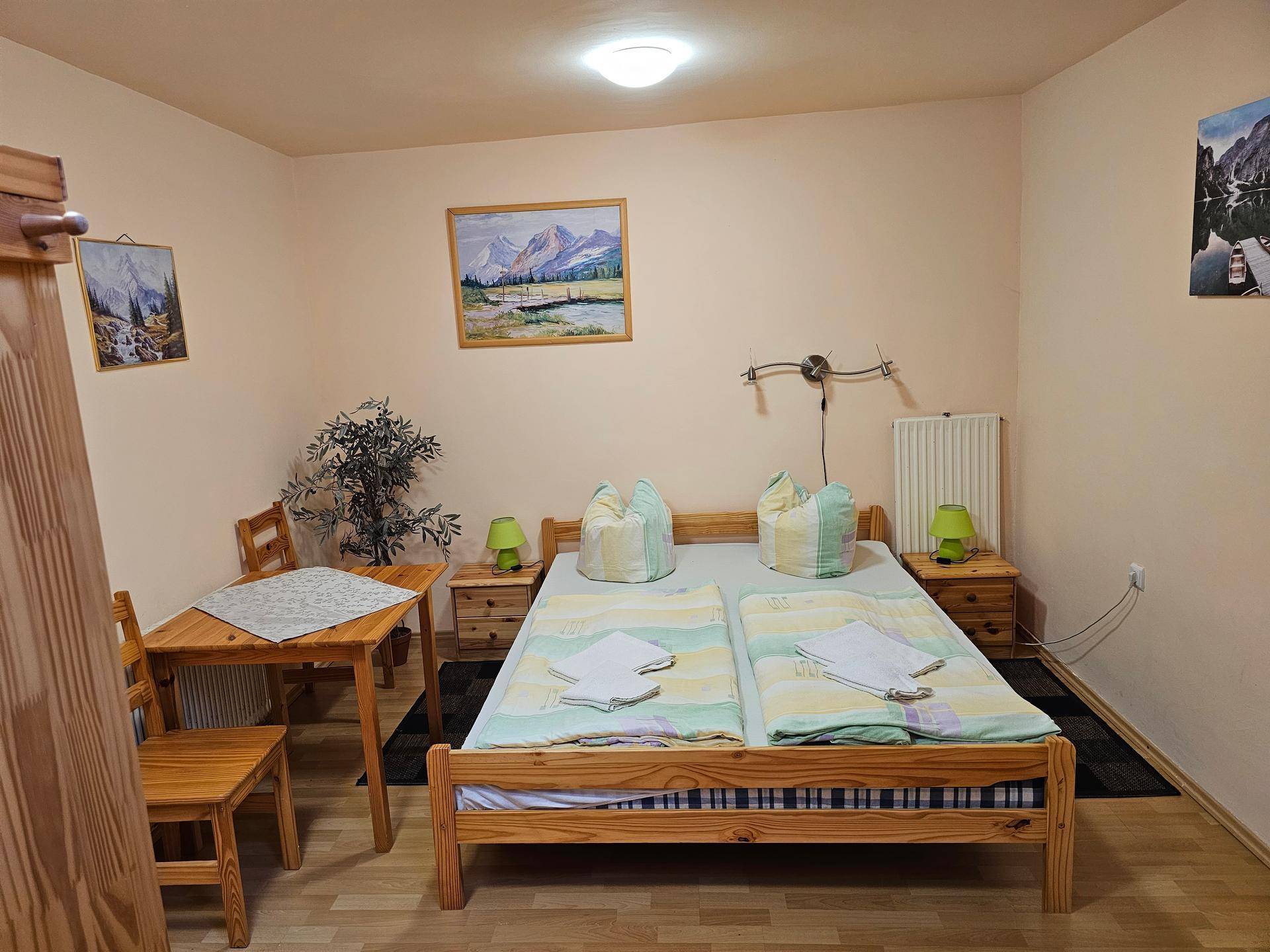 Helles Schlafzimmer mit zwei Einzelbetten, einem kleinen Tisch und Bildern an den beigen Wänden.