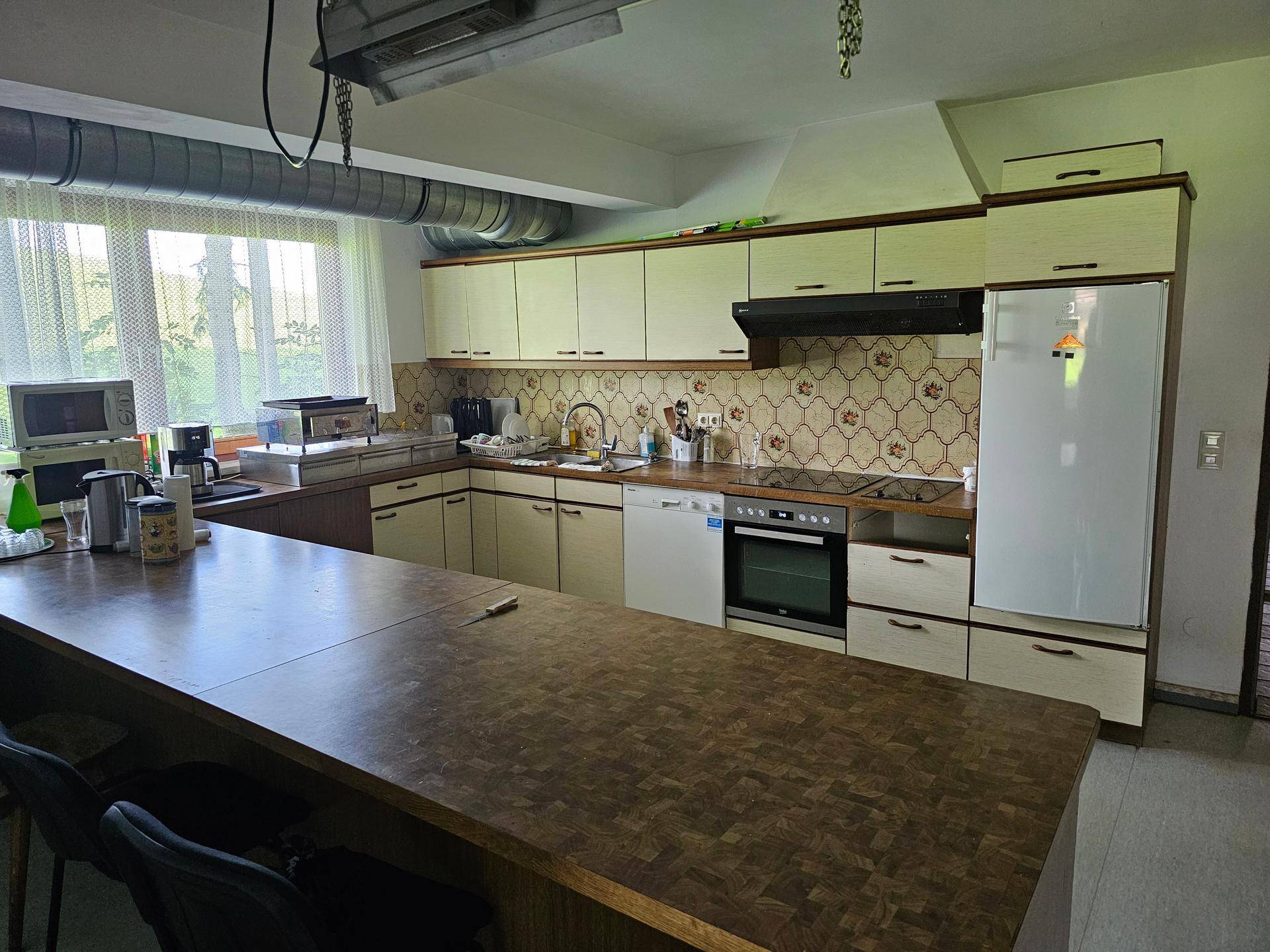 Große Küche mit langer Holztheke, weißen Schränken und verschiedenen Küchengeräten.