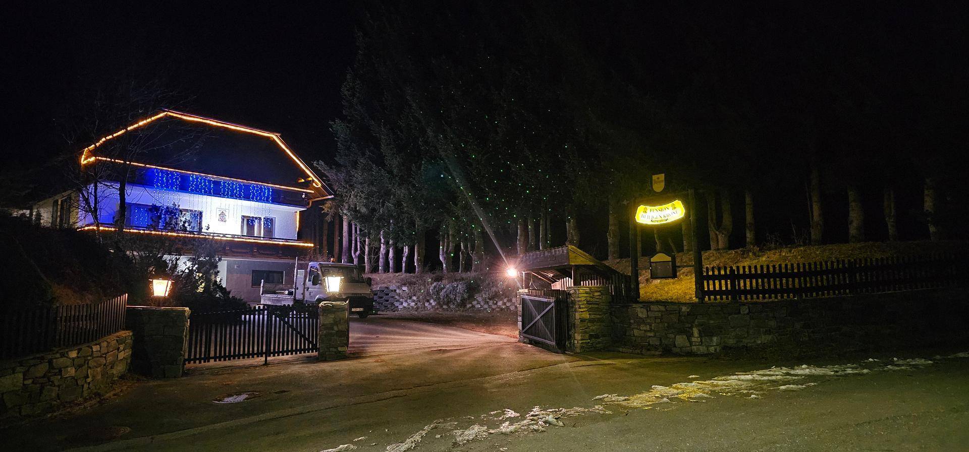 Das Anwesen bei Nacht, festlich beleuchtet mit Lichterketten, umgeben von dunklen Bäumen.