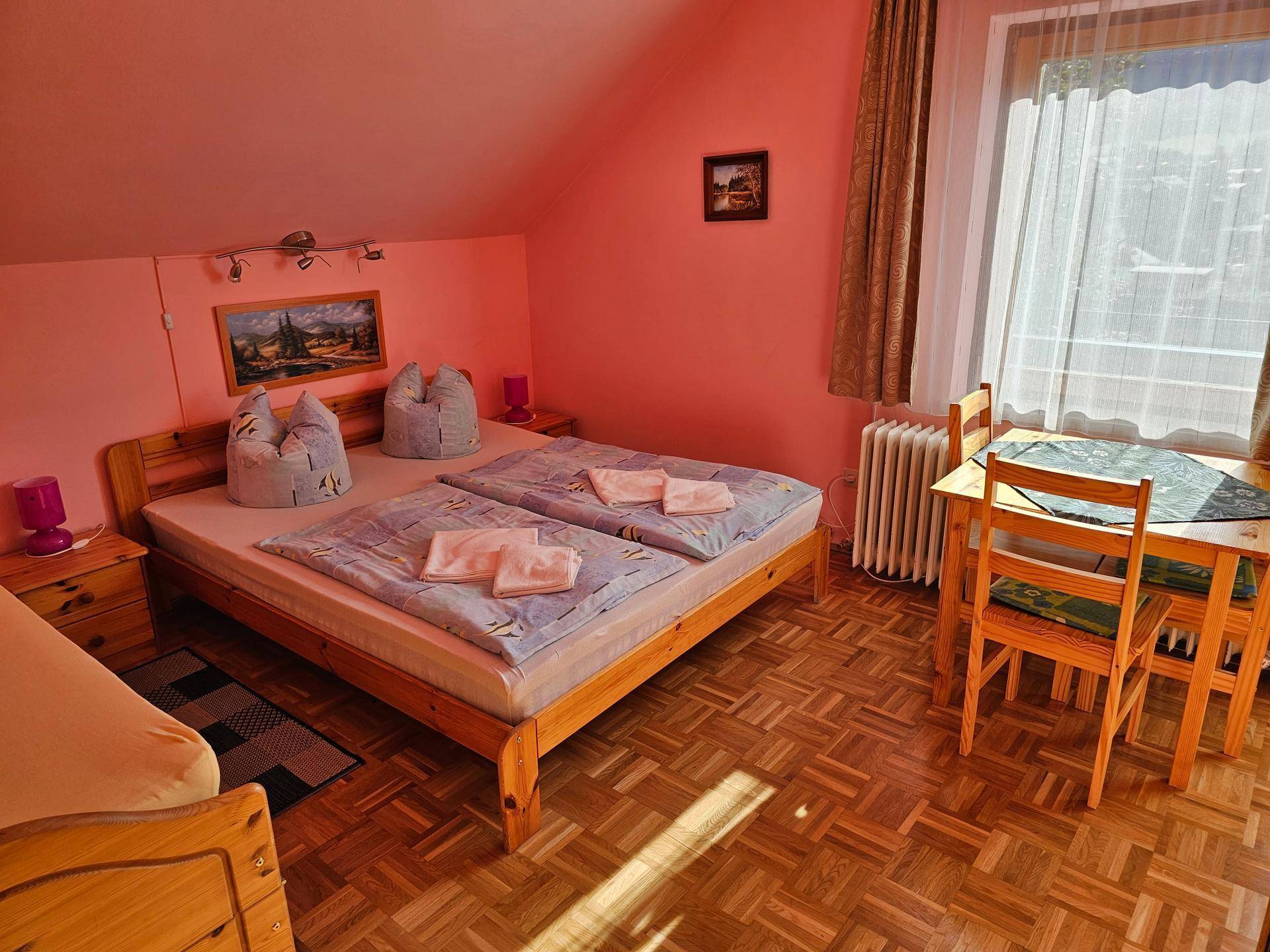 Gemütliches Schlafzimmer mit zwei Einzelbetten, einem kleinen Tisch und rosa Wänden.