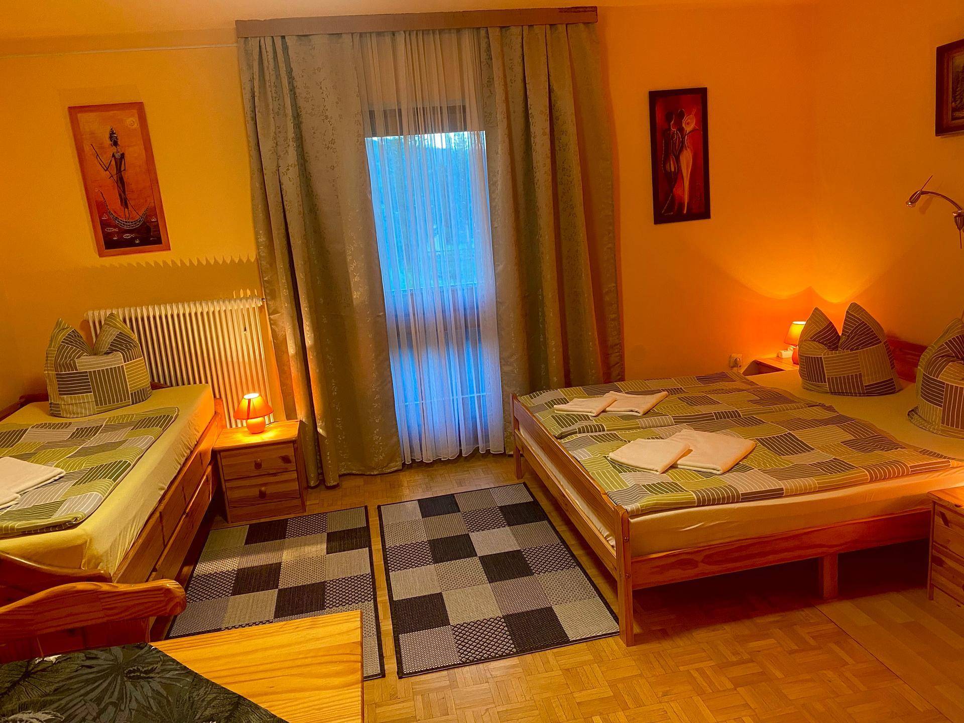 Schlafzimmer mit zwei Einzelbetten, einem kleinen Tisch und einem Fenster mit Vorhängen.